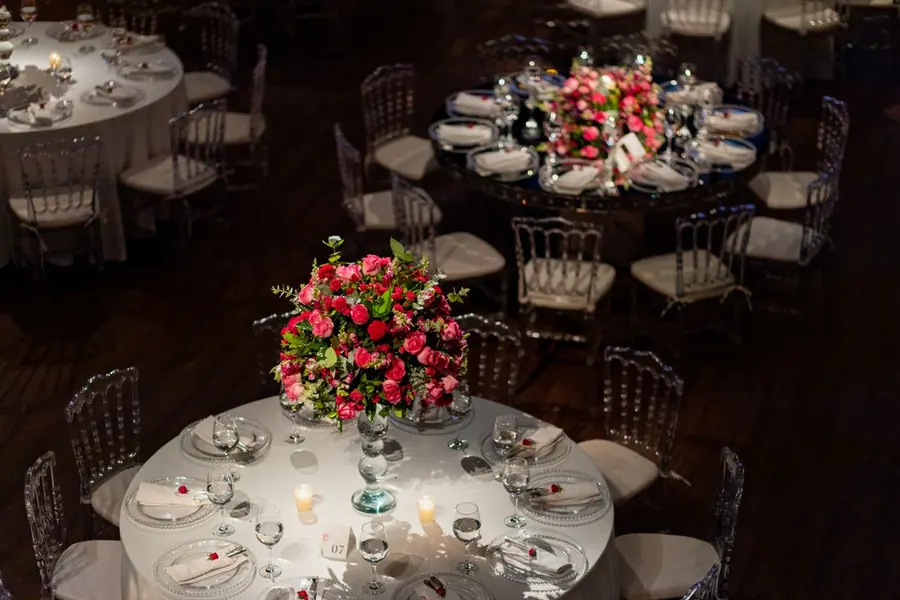 Ronde dinertafels met bloemstukken en kaarsen, gedekt voor een bruiloftsdiner